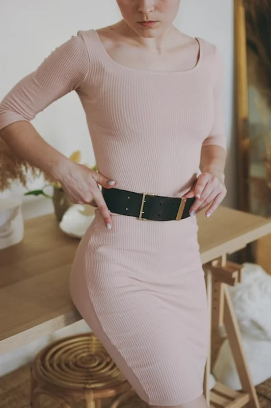 Młoda dziewczyna w różowej sukience przymierza skórzany pasek