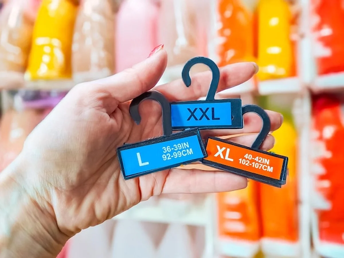 Kobieta trzyma etykiety odzieży różnych rozmiarów