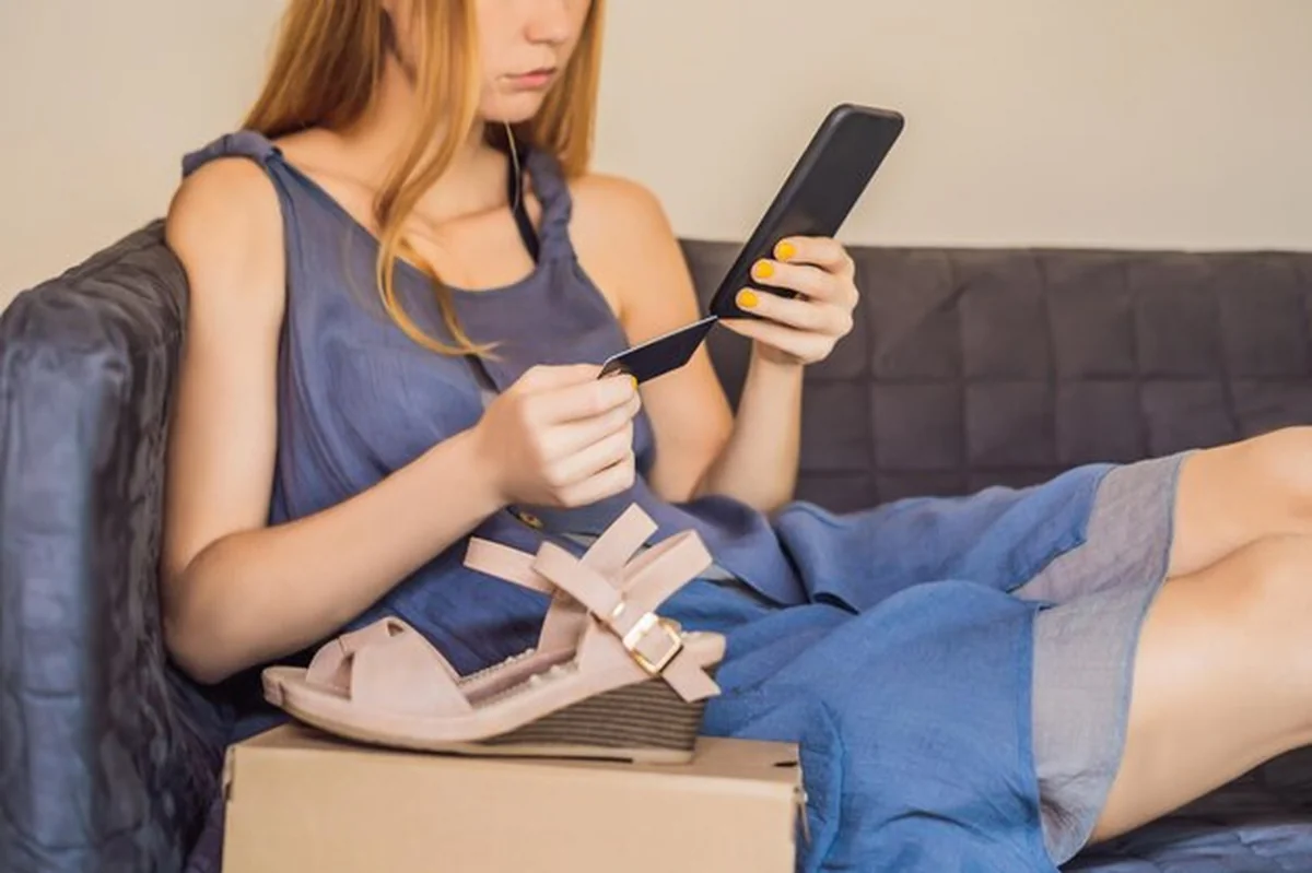 Młoda kobieta otwiera pudełka z zakupami online płacąc kartą kredytową