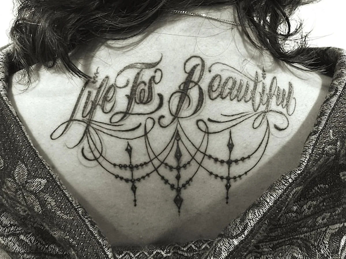 Tatuaż na plecach kobiety z długim cytatem