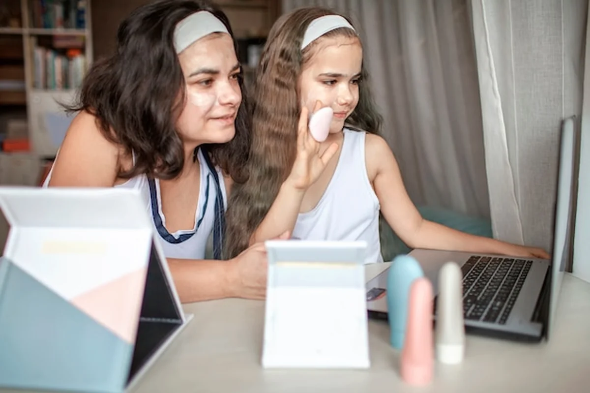 Dziewczyna i matka robią sobie zabiegi spa z gładką maską na twarzy, korzystając z lekcji piękna online na tabletach