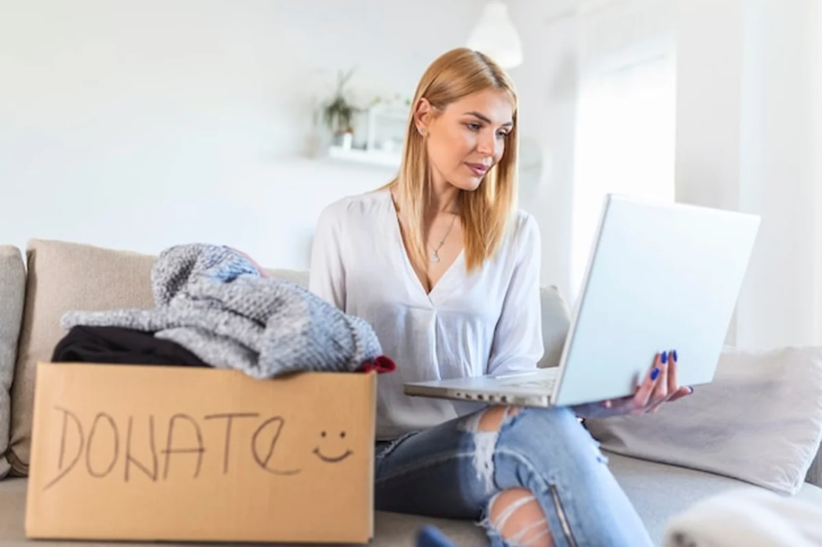 Kobieta pakująca ubrania do pudełka z napisem 