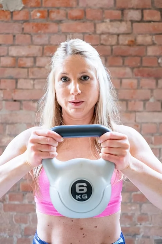 Młoda blondynka trenuje z kettlebellami w garażu