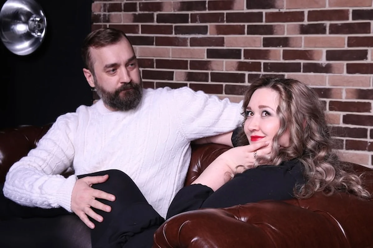 Mężczyzna patrzy na myślącą kobietę siedzącą na kanapie przy ceglanej ścianie