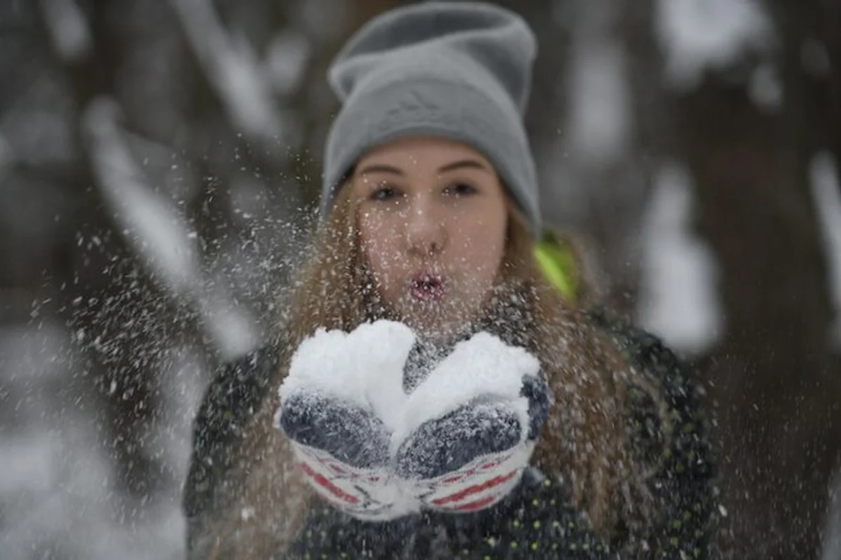 Młoda kobieta dmuchająca śnieg w zimie