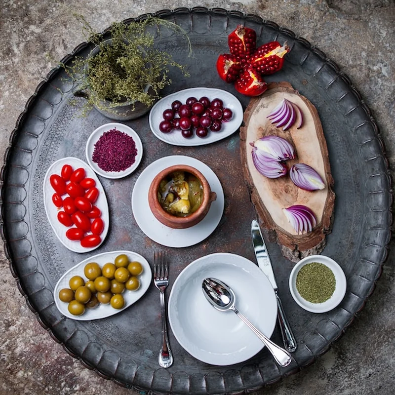 Piti w glinianym garnku z oliwkami, cebulą i granatem na miedzianej tacce