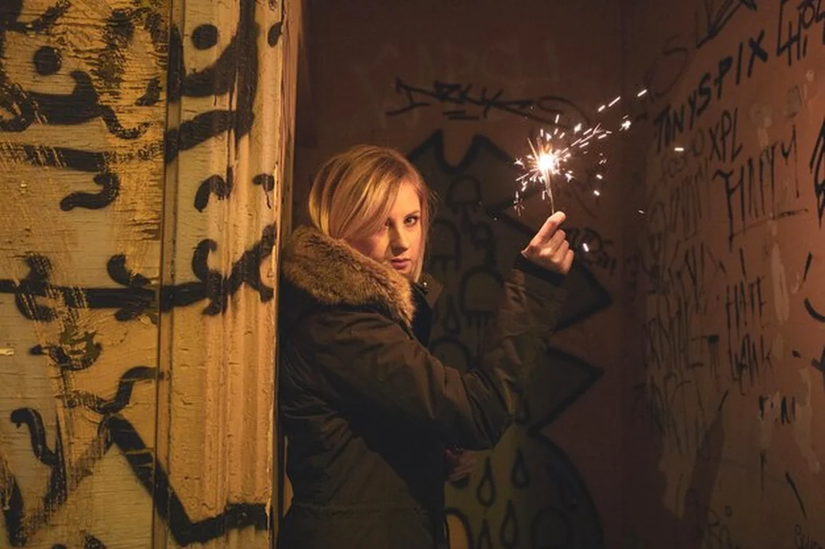 Kobieta trzymająca błyszczącą lampę w ciemności