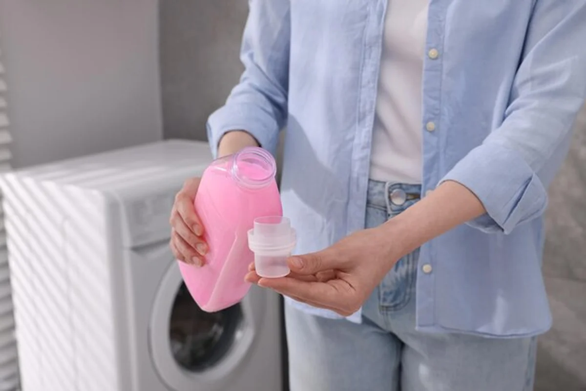 Kobieta wlewa płyn do płukania z butelki do czapki w pomieszczeniu zamkniętym