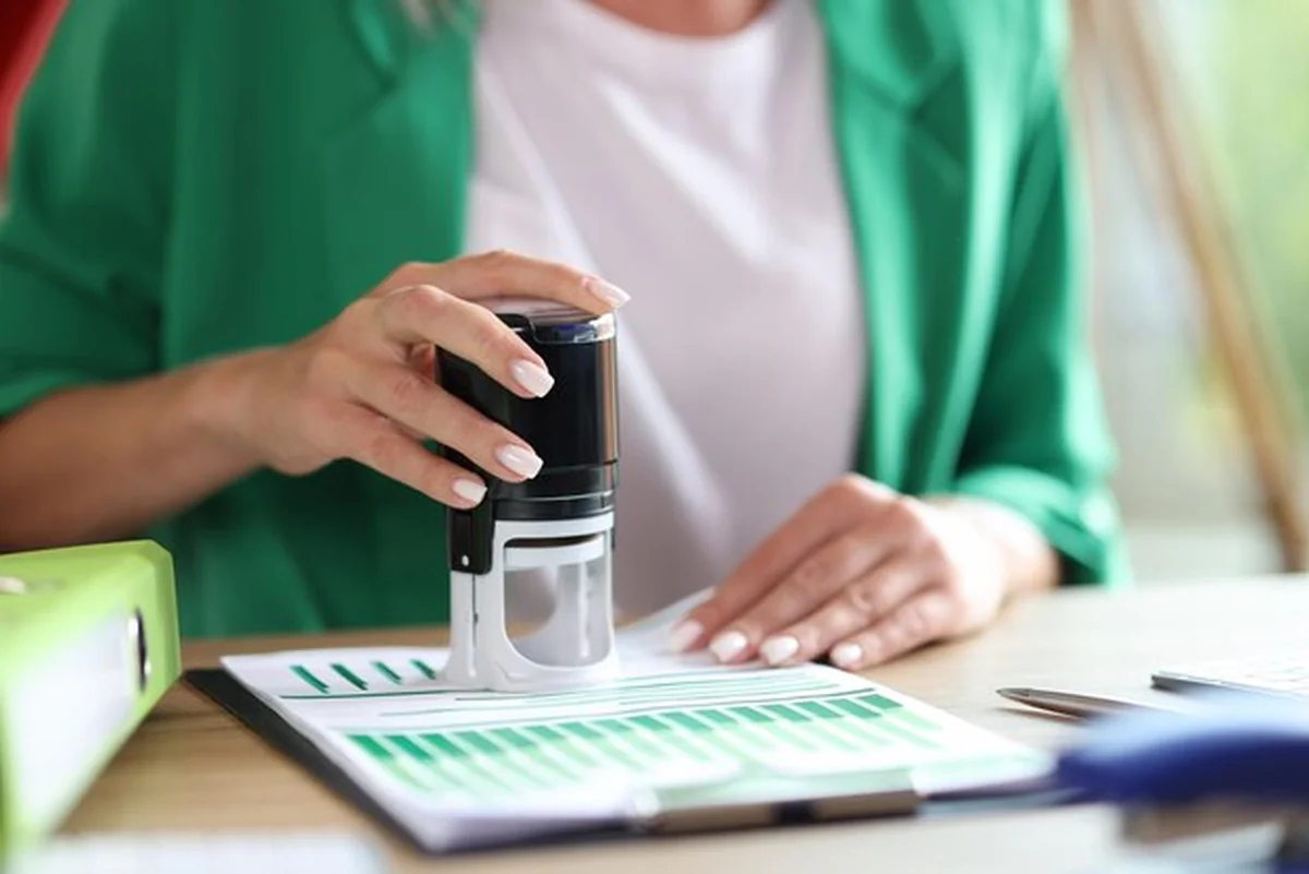 Ręka trzymająca pieczątkę i stemplująca dokumenty biznesowe