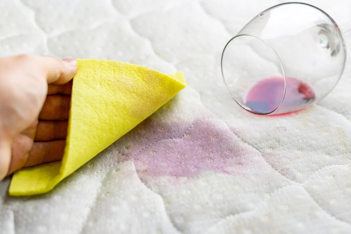 Osoba sprzątająca plamę wina na łóżku