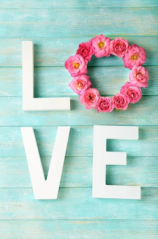 Piękne róże ze słowem MIŁOŚĆ na tle drewnianych desek