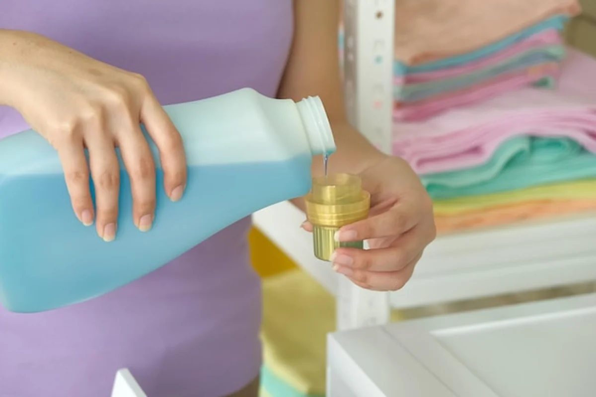 Ręce kobiety wylewają detergent do kubka prania bielizny